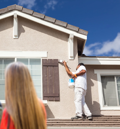Exterior painter applying fresh coat of paint to window shutters on a residential home in Orlando, FL