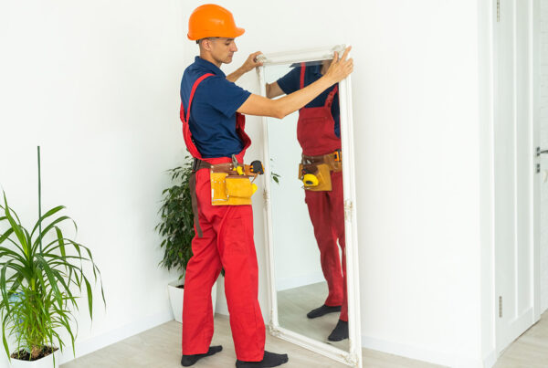 Handyman aligning and installing a full-length mirror in a modern Orlando, FL home