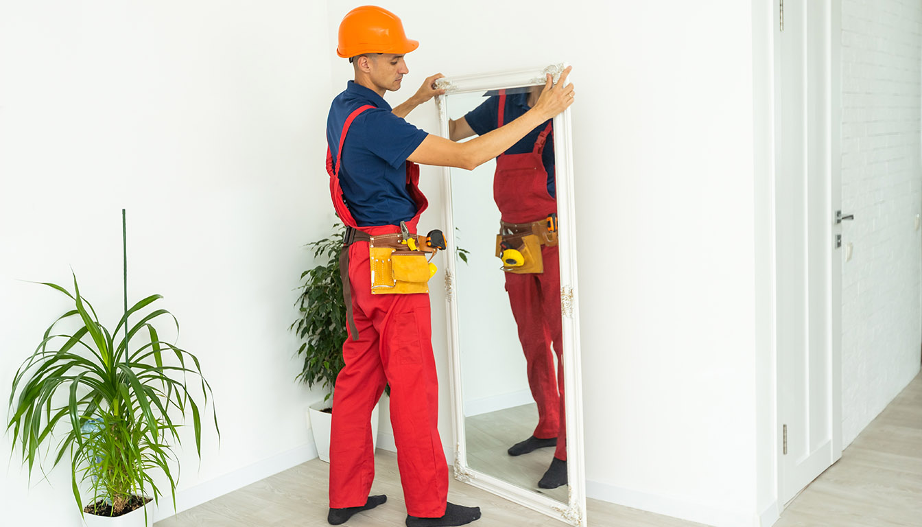 Handyman aligning and installing a full-length mirror in a modern Orlando, FL home