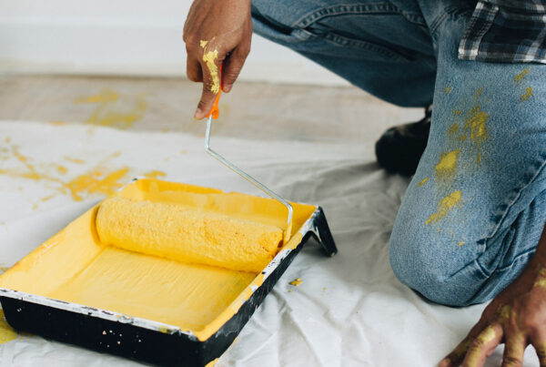 Handyman prepping yellow paint with roller during professional painting service in Orlando, FL