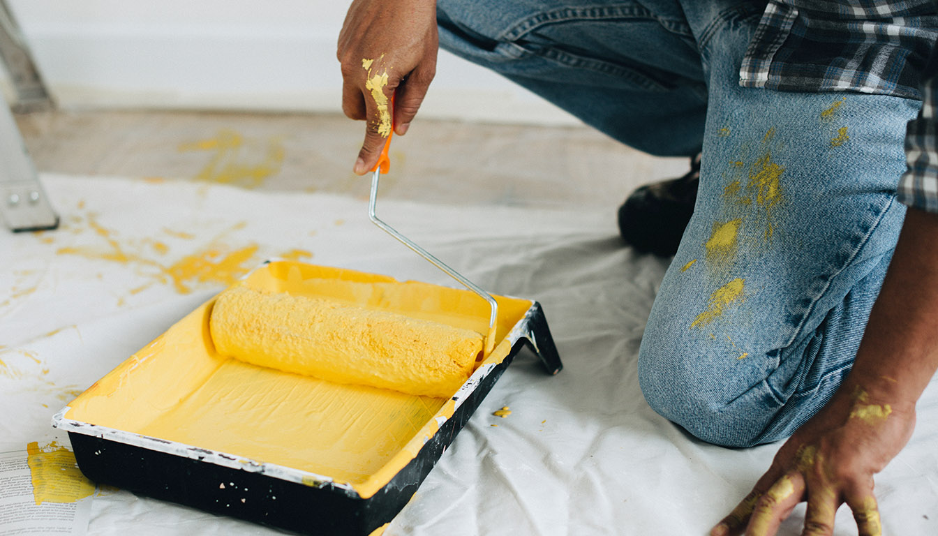 Handyman prepping yellow paint with roller during professional painting service in Orlando, FL