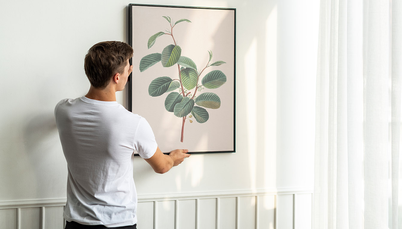 Man hanging framed picture on interior wall during professional picture hanging service in Orlando, FL
